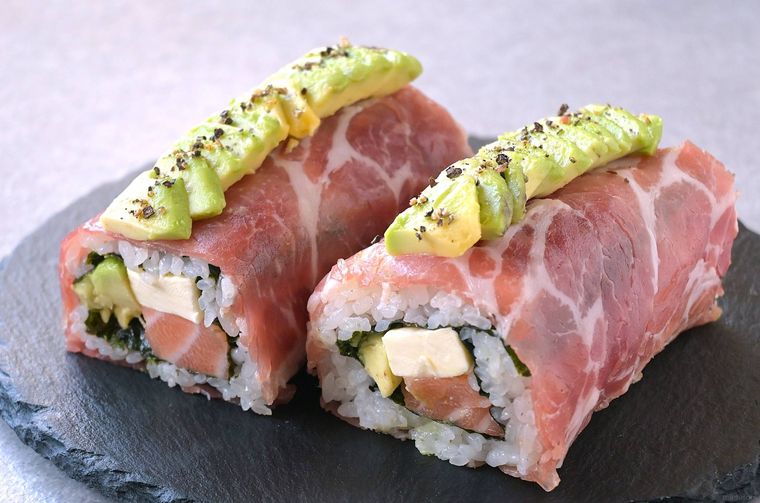 黒いスレート皿に盛り付けられた2本の生ハムロール寿司