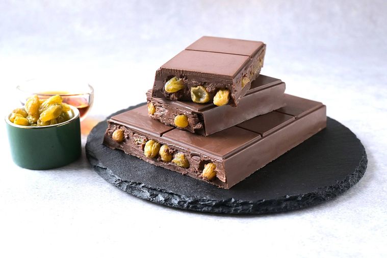 黒いスレート皿に盛り付けられたラムレーズンチョコレートの断面からレーズンが見えている