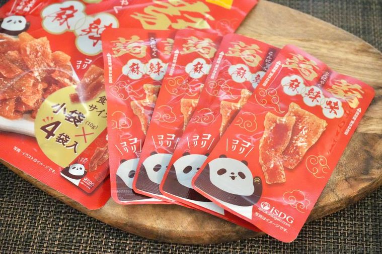 木のカッティングボードにのった赤いパッケージのおつまみの個包装