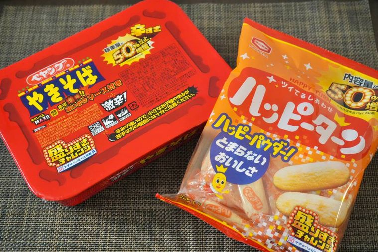 赤い激辛カップ焼きそばとオレンジ色のせんべいのパッケージ