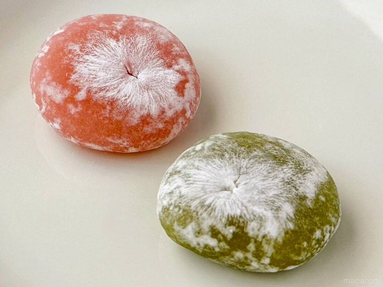 白皿にのった桜と抹茶のひとくち大福がテーブルの上に置かれている様子