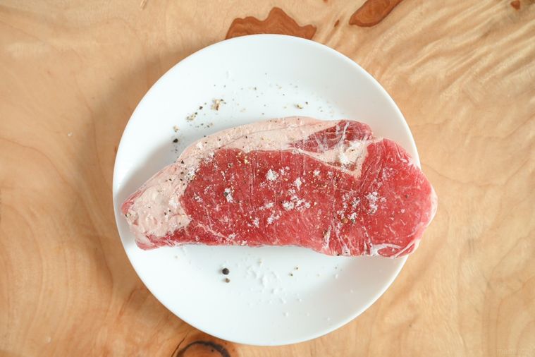 白い皿にのった塩・こしょうをしたステーキ肉