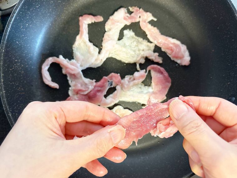 フライパンに豚こま肉を広げながら入れる様子