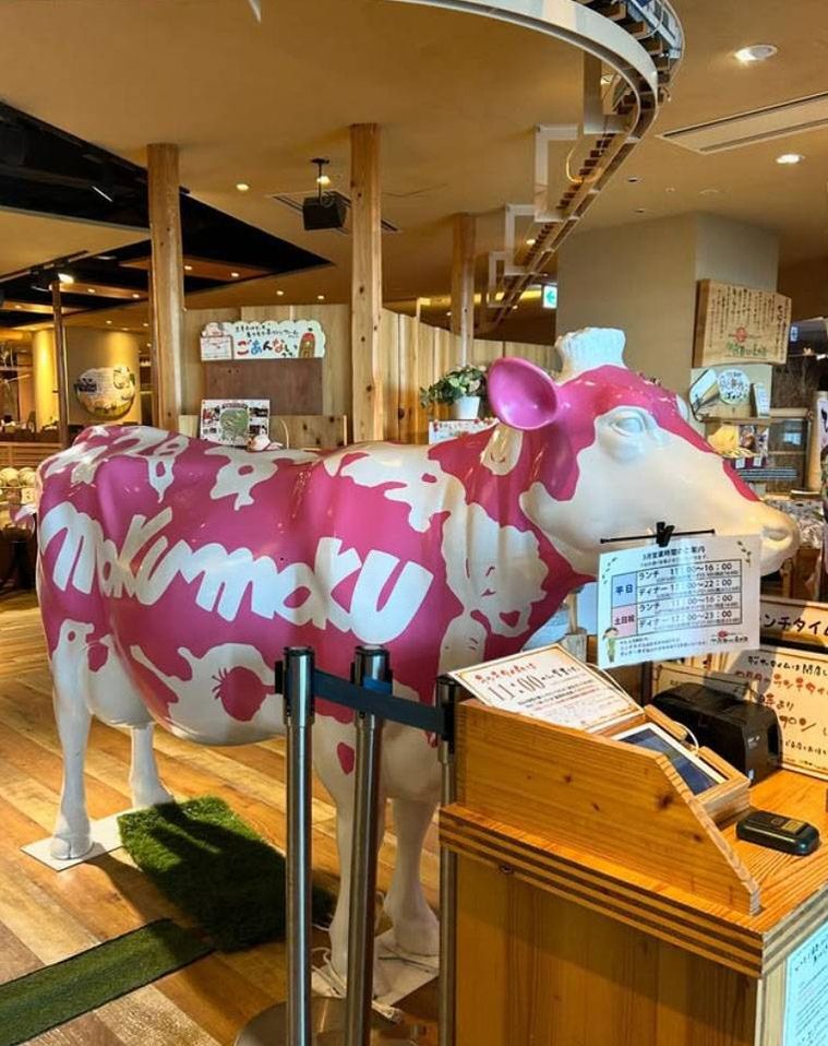 牛のモニュメントが置かれたモクモク直営農場レストラン お日さまのえがおの外観