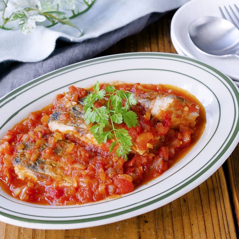 緑のラインが入った白い皿に盛り付けられた鯖のトマト煮