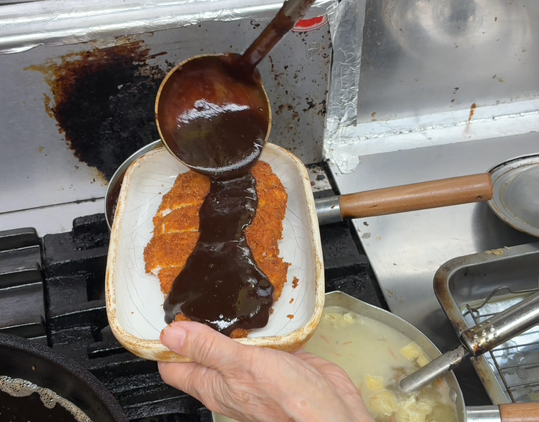 カツに味噌ソースをかけているところ