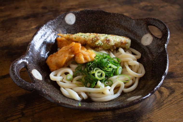 にんべん黒酢玉ねぎめんつゆを使ったうどんが木製のテーブルに置かれている