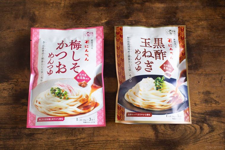 にんべん黒酢玉ねぎめんつゆと梅しそかつおめんつゆのパッケージが木製のテーブルに並んでいる