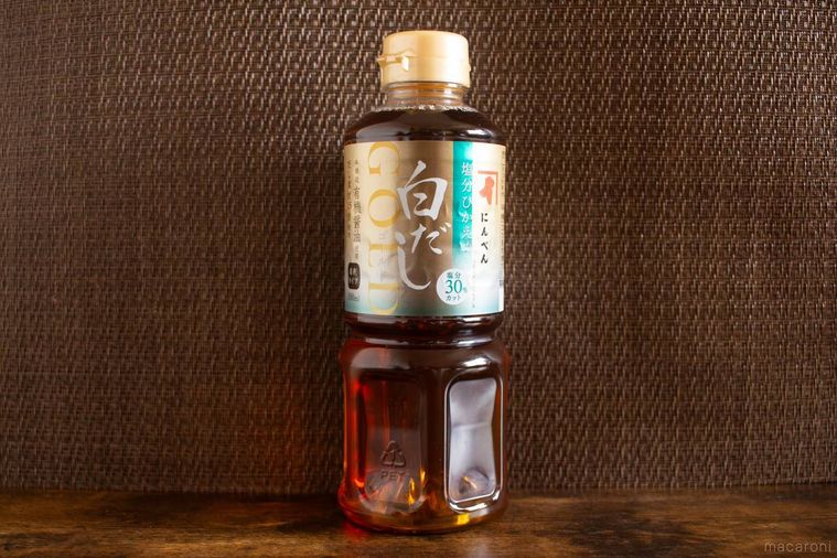 にんべん塩分ひかえめ白だしゴールド 500mlのボトルが木製のテーブルの上に立っている