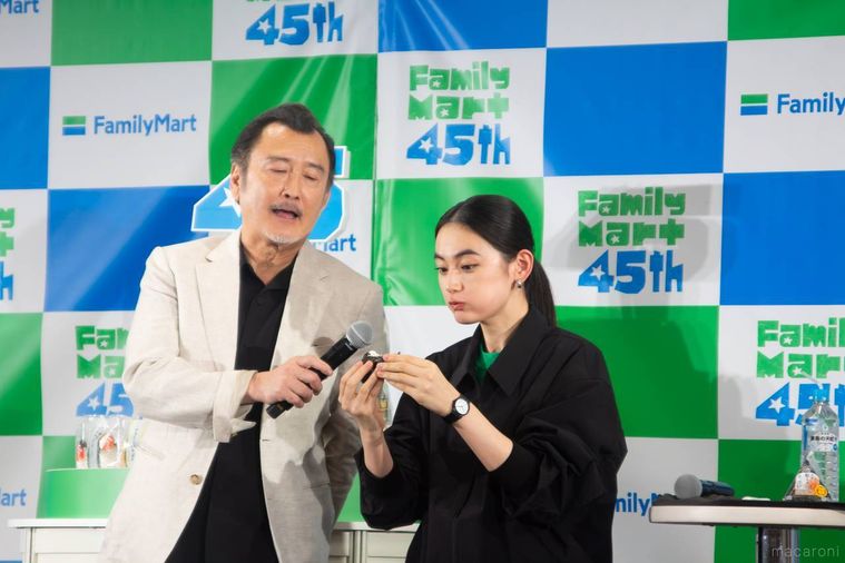 ファミマのおむすびを食べている八木莉可子さんと八木さんにマイクを向けている吉田鋼太郎さん