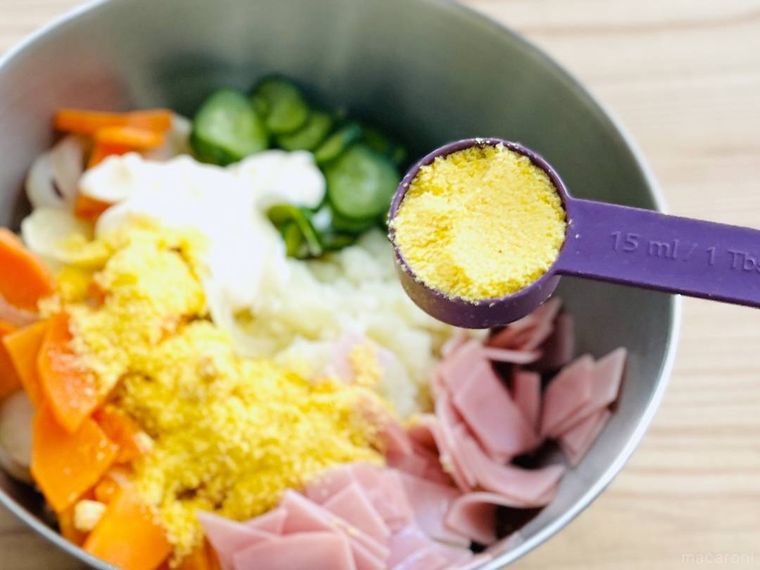 ポテトサラダの具材が入ったボウルに、コーンポタージュの素を入れている様子