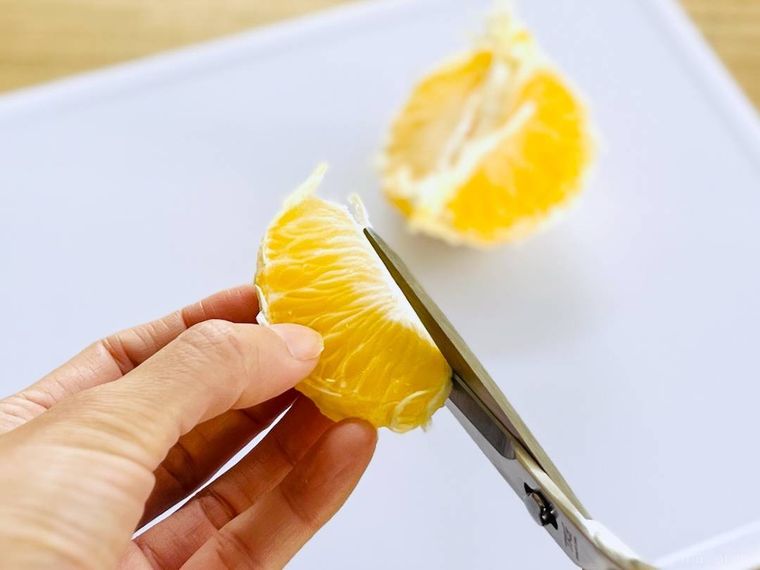 はっさくの房の上部をキッチンバサミで切り落としている様子