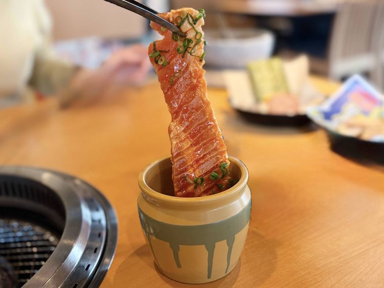 トングで持ち上げている壺漬けすだれ豚バラカルビ