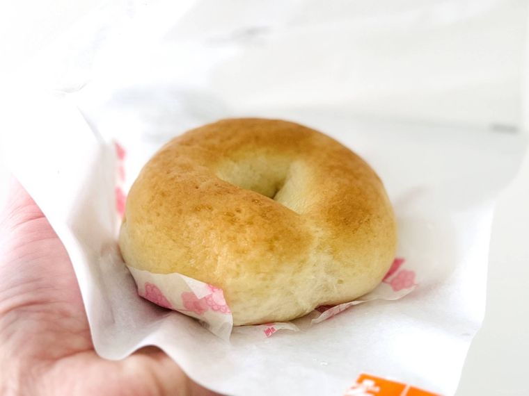 セブンイレブンのもっちり食感のチーズベーグルを手で持っている様子