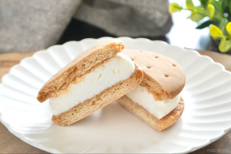 木のカッティングボードと白い皿にのったクリームビスケットサンドの断面