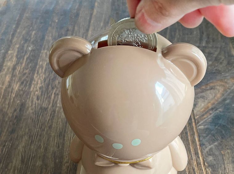 くま貯金箱にコインを入れている様子