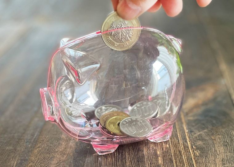 ぶたの貯金箱にコインを入れている様子