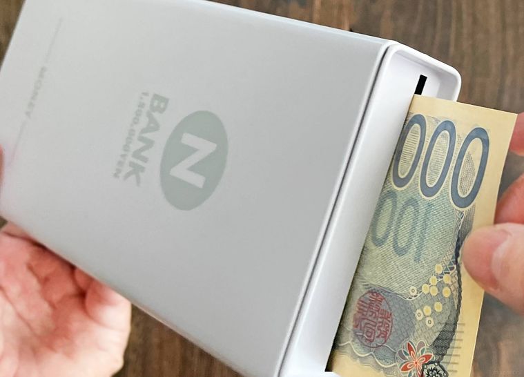 お札用貯金箱にお札を入れている様子