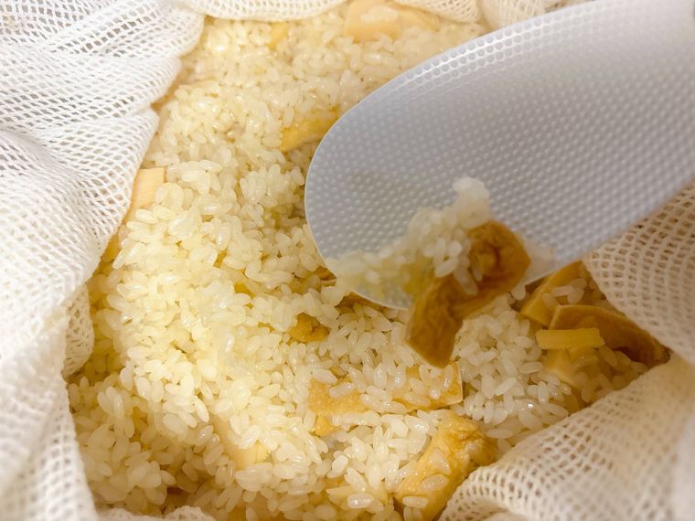 たけのこおこわをしゃもじですくう様子