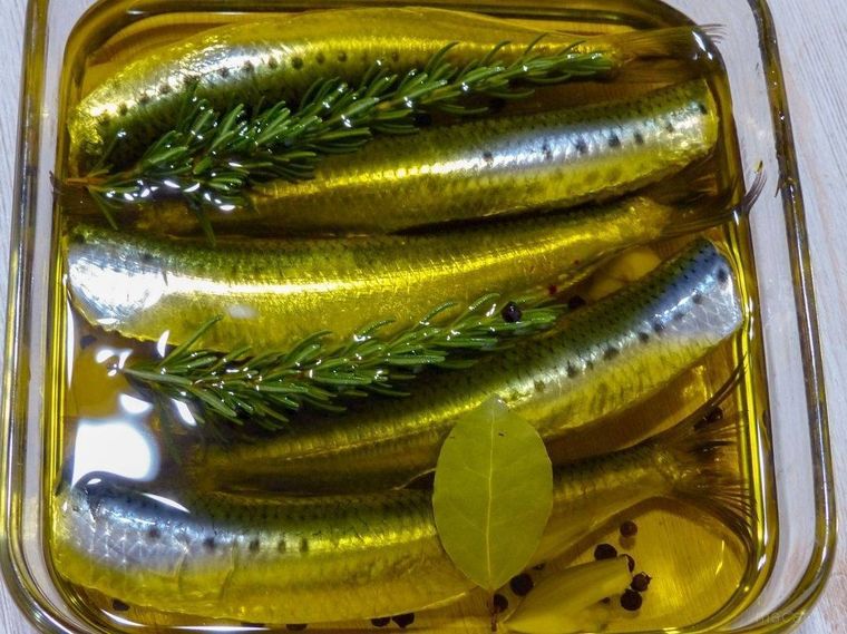 いわしとオリーブオイル、ハーブやスパイスをガラス容器に入れた様子