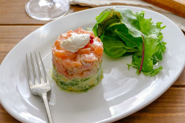 サーモンタルタルとベビーリーフを盛り付けた白い皿