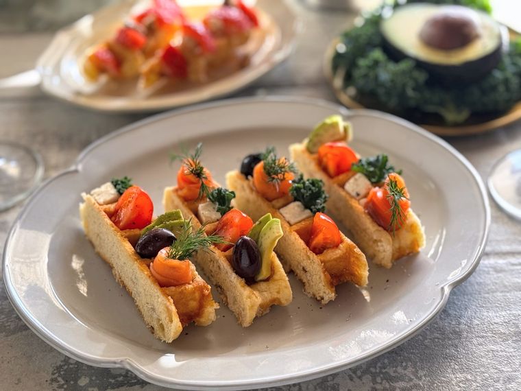 オーバル皿にのったアレンジワッフル4つと奥にアボカドやスイーツが見えている様子