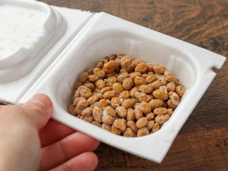 パックに入った納豆を手で持っている