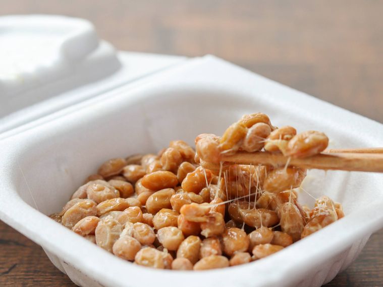 パックに入った納豆を箸で持ち上げる