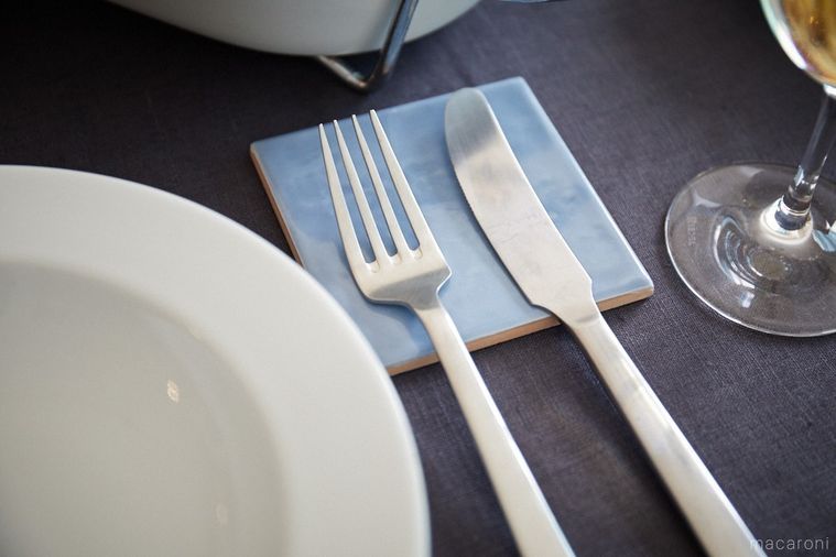 水色のタイルの上にのせたフォークとナイフ