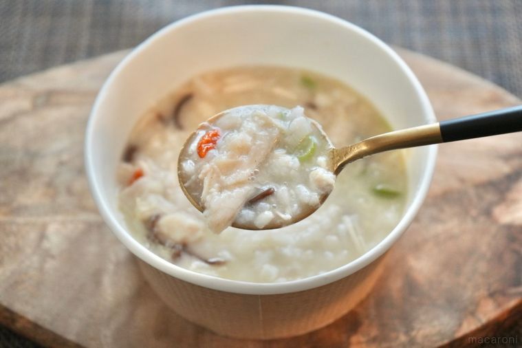 木のカッティングボードにのった冷凍スープご飯の参鶏湯を金のスプーンですくう様子