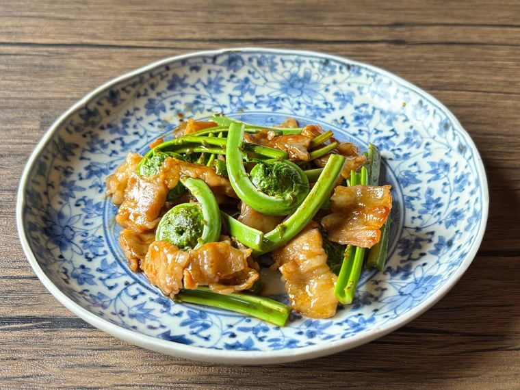 和皿に盛られたこごみと豚バラの中華炒め