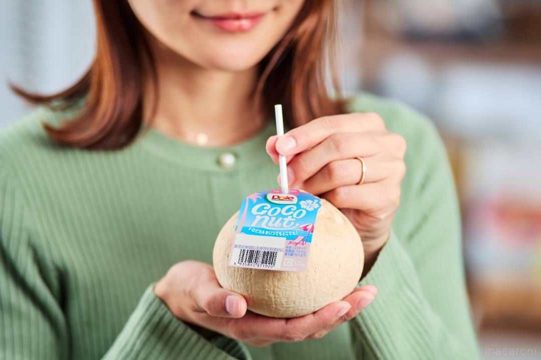 女性がココナッツにストローを刺して飲んでいる様子