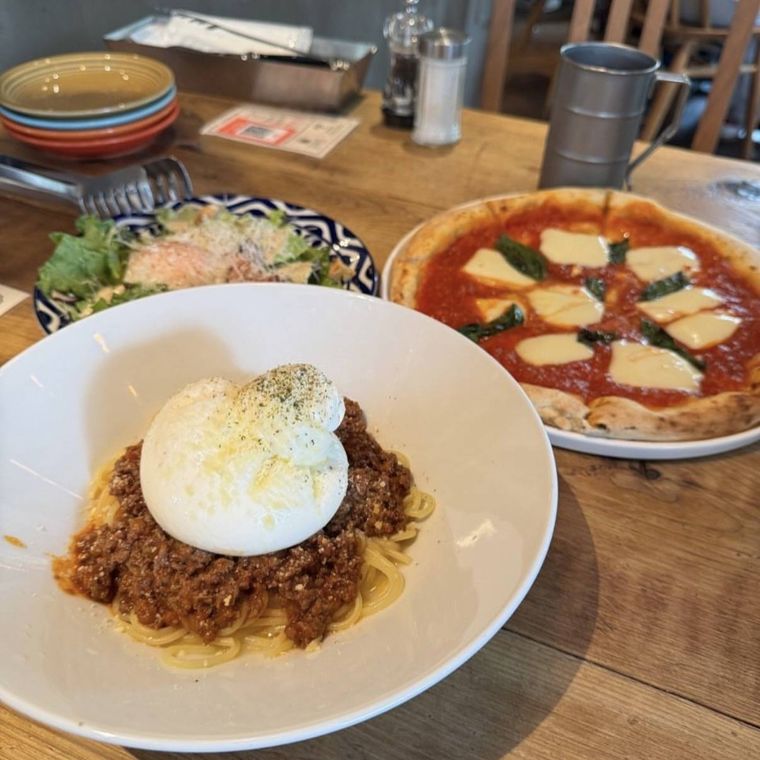 テーブルに並んだモッツァレラボロネーゼとピザ