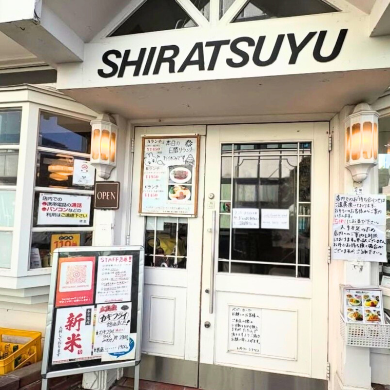 白い扉と外壁にSHIRATSUYUと大きなロゴが入った外観