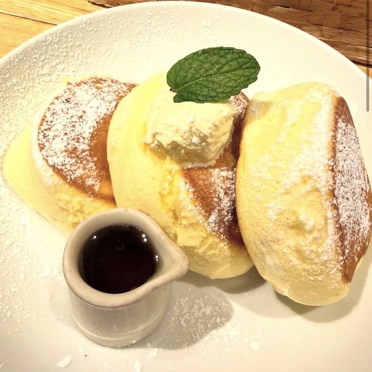 こんがり焼き色のついたパンケーキ3枚とシロップ、ミント添え