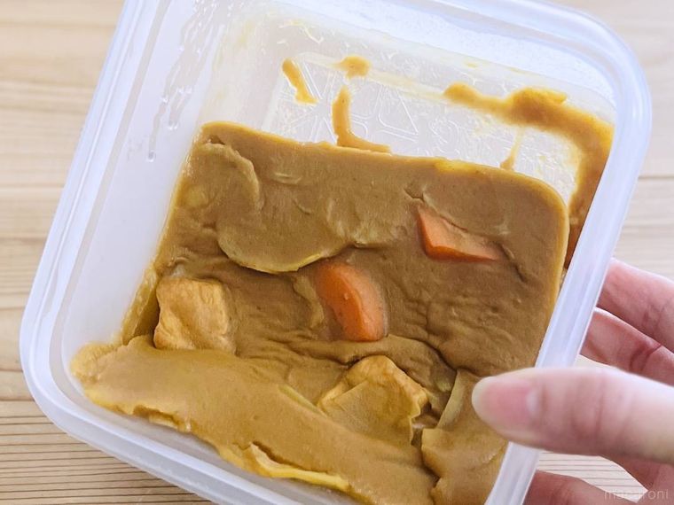 カレーが入った保存容器を傾けている様子