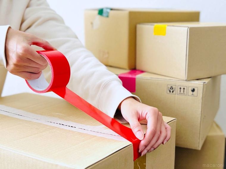 赤いカラーテープでダンボールの蓋を閉じている様子