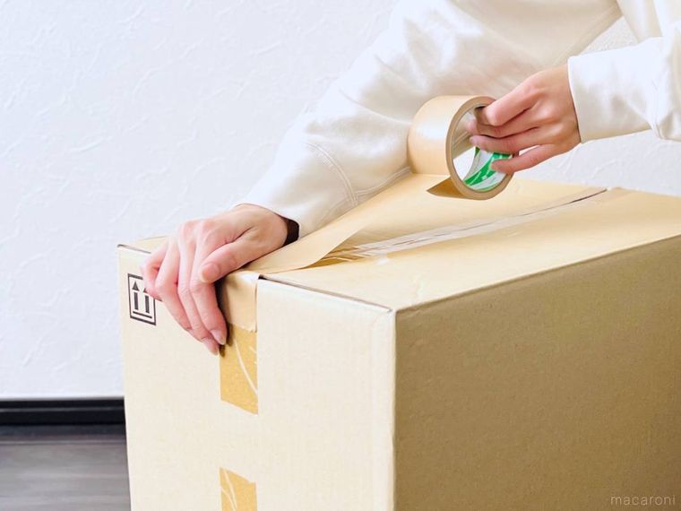 ガムテープでダンボールの蓋を閉じている様子
