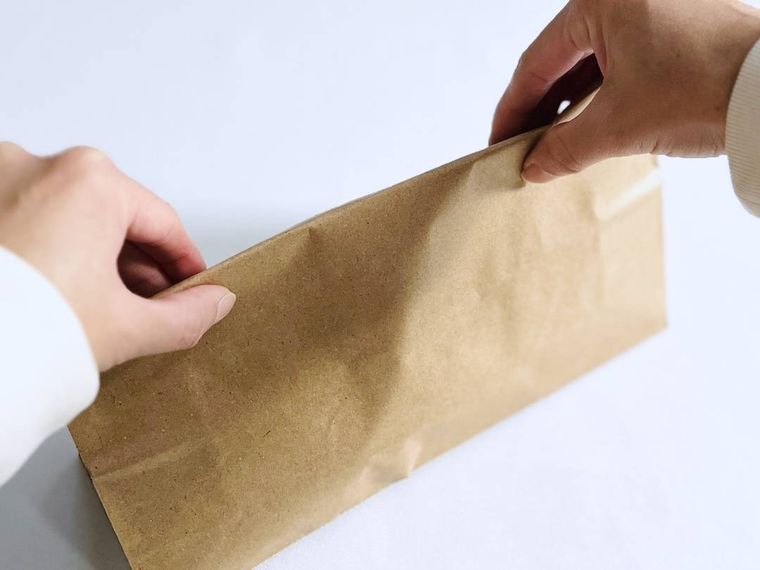 バナナが入った紙袋の口を閉じている様子
