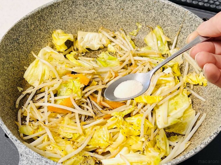 野菜炒めに粉末寒天を入れようとしている様子