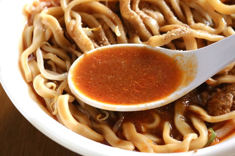 辛いスープをすくっている