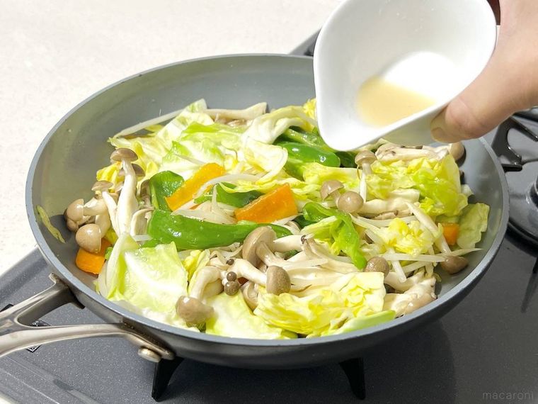 野菜炒めに調味料を加えようとしている様子