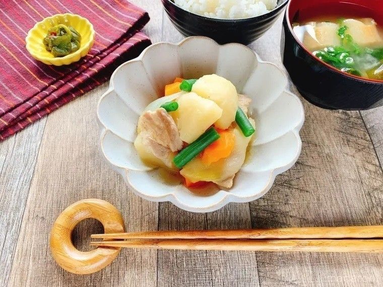 白い和皿に盛られた時短豚肉じゃがに、ごはんや味噌汁などが添えられている様子