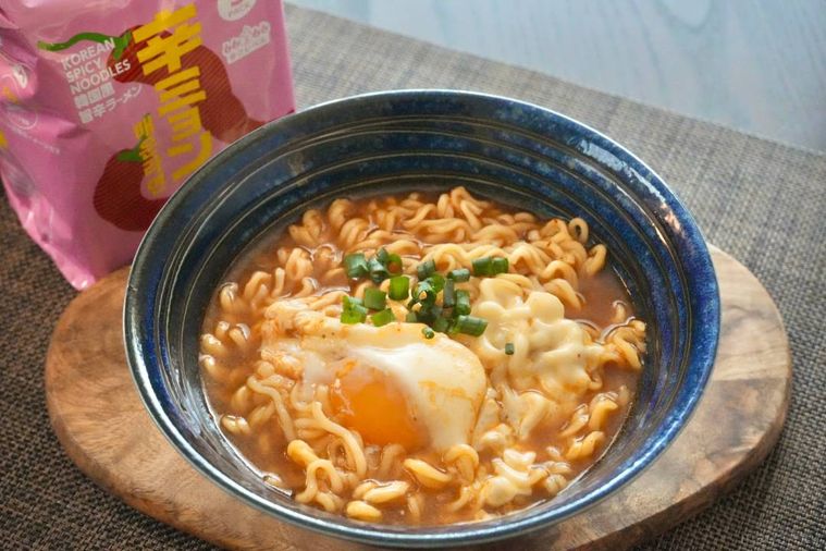 青い丼に卵とネギと盛られた韓国風旨辛インスタントラーメン