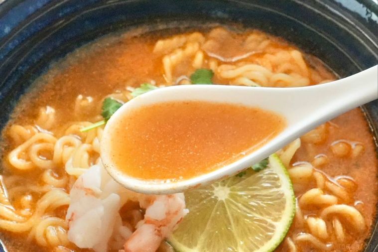 トムヤムクンインスタントラーメンのスープを白いれんげですくう様子