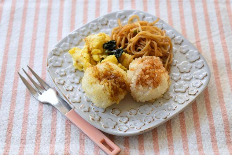 皿に盛った小さい焼きおにぎり2個、焼きそば、卵焼き