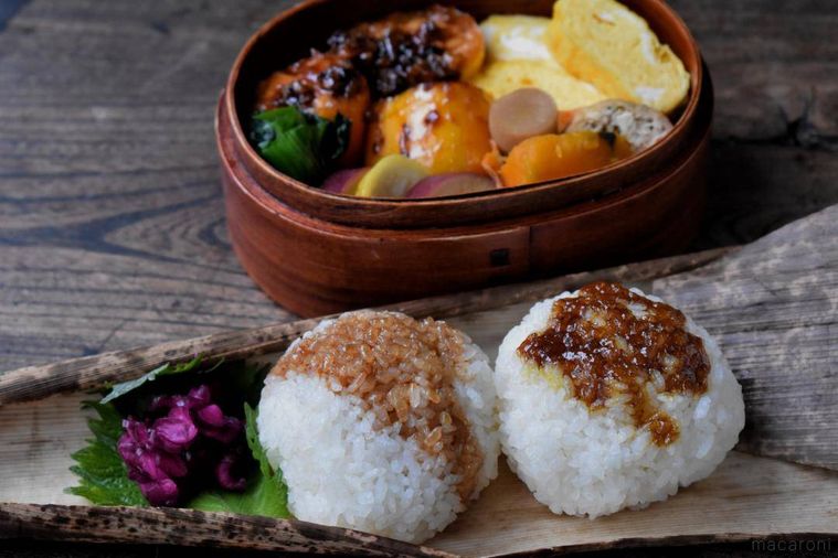 竹皮に置いた焼きおにぎり2個、わっぱに詰めたおかずのお弁当