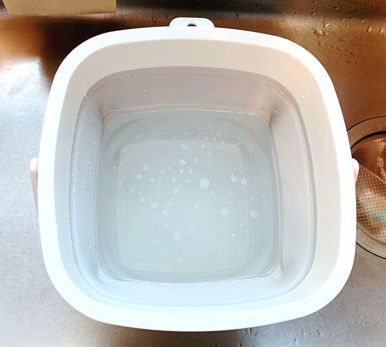 桶に漂白剤をうすめた液を作っている