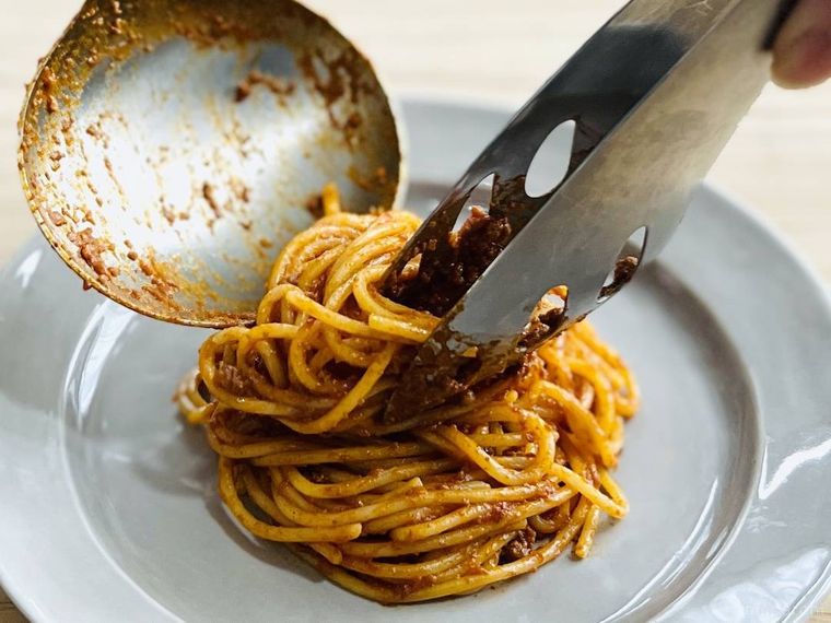 ボロネーゼパスタを皿に盛り付けている様子