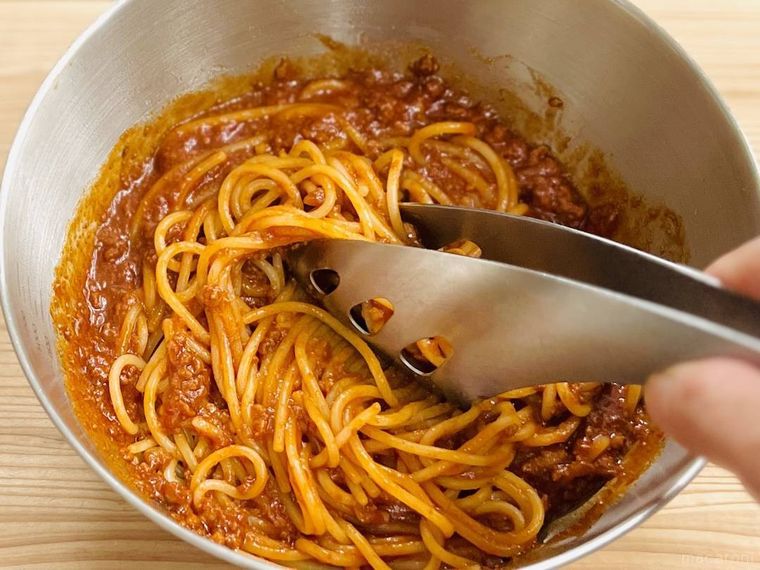 パスタをボロネーゼソースと和えている様子